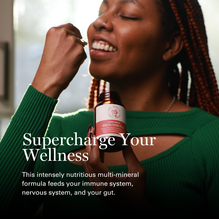 Woman holding Dr. Sebi's Green Food Plus bottle, smiling with eyes closed in wellness moment.