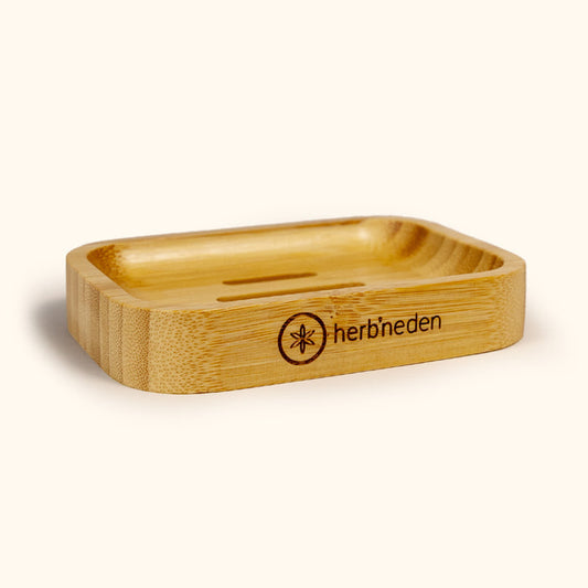 Rectangular bamboo soap dish with drainage slots and Herb’n Eden logo, shown at an angle on a neutral background.