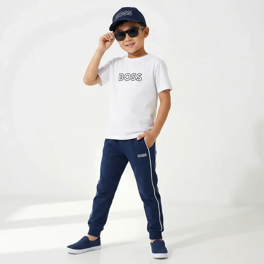 Child wearing a white  t-shirt, navy pants, and cap on a white background